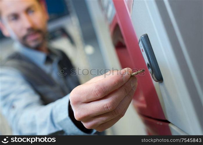 close up of man inserting coin into vending machine