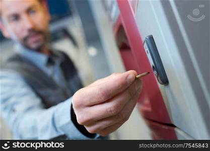 close up of man inserting coin into vending machine