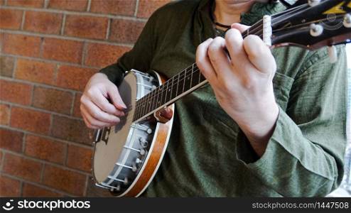 Close Up of Man playing Banjo against Brick Background