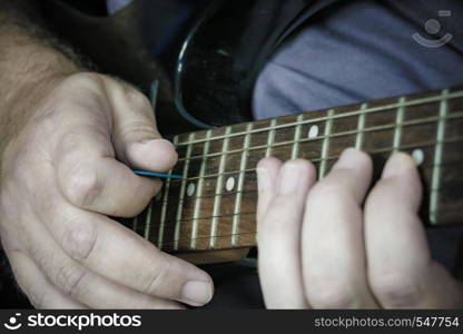 Close-up of man playing lead guitar solo on black guitar