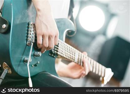 Close up of man playing on electric guitar during gig or at music studio. Musical instruments, passion and hobby concept.. Close up of man playing on electric guitar
