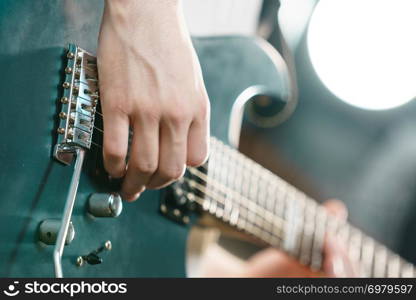 Close up of man playing on electric guitar during gig or at music studio. Musical instruments, passion and hobby concept.. Close up of man playing on electric guitar