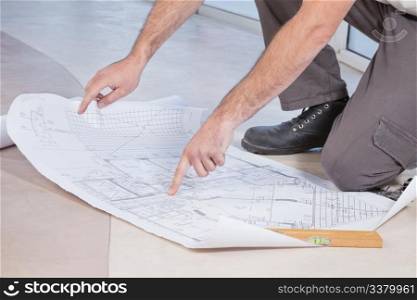 Close-up of man pointing finger at blueprint