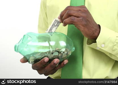 Close up of man putting a dollar in a piggy bank. USD.