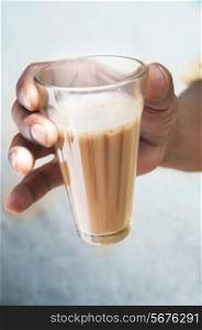 Close-up of man&rsquo;s hand holding glass of chai