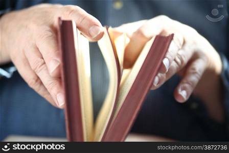 close-up of man&rsquo;s hands as he leafs through pages