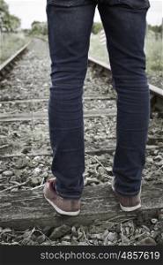 Close-Up Of Man's Feet Standing Between Railway Tracks