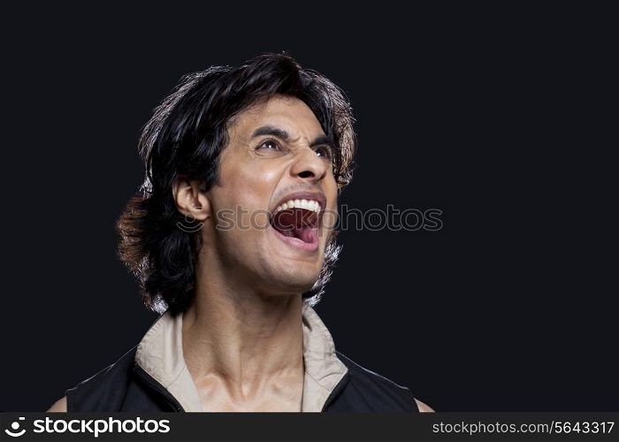 Close-up of man shouting while looking up against black background