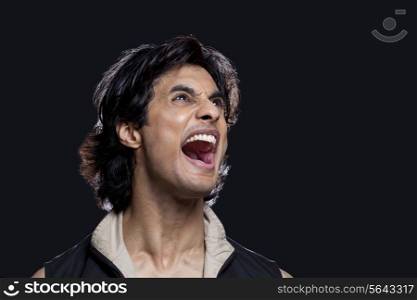 Close-up of man shouting while looking up against black background