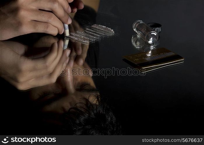 Close-up of man snorting drugs through rolled up banknote