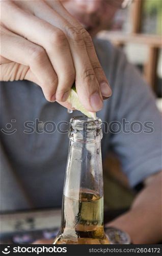 Close-up of man squeezing lime into beer