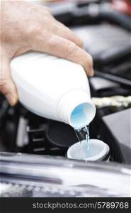 Close-Up Of Man Topping Up Windshield Washer Fluid In Car