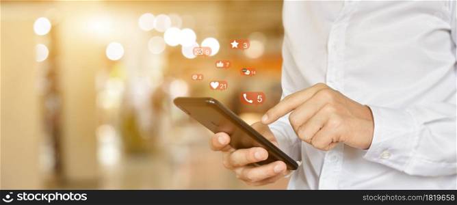 Close up of man using mobile smartphone with social, media icons. Marketing or business technology concept.