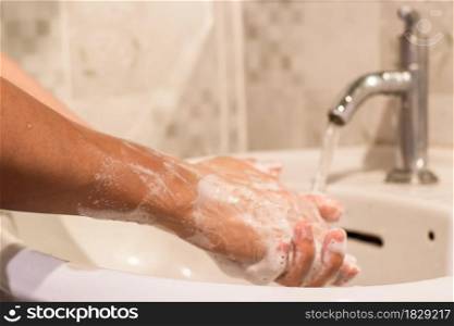 Close-up of man washing hands with soap over sink in bathroom. hygiene treatment