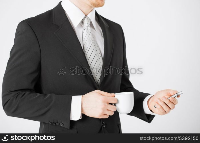 close up of man with smartphone and cup of coffee