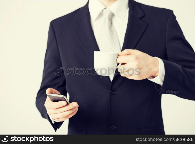 close up of man with smartphone and cup of coffee