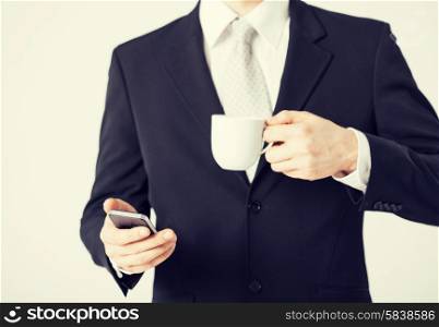 close up of man with smartphone and cup of coffee