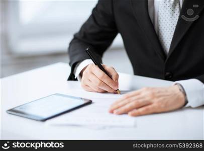 close up of man with tablet pc signing paper