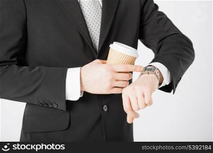 close up of man with take away coffee looking at wristwatch