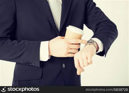 close up of man with take away coffee looking at wristwatch