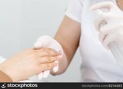 Close up of manicurist moisturising fingernails of woman by thermal water.. Manicurist is moisturising fingernails by thermal water.