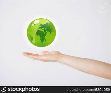 close up of mans hand holding green globe