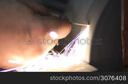 Close up of manual sharpening of tool on grinding machine in workshop.