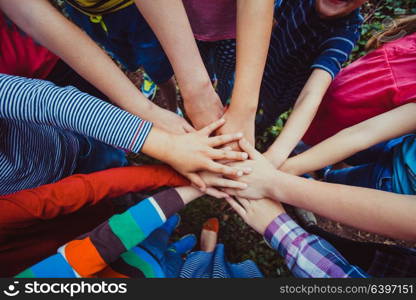 Close-up of many children&rsquo;s hands holding together as a team on a nature background. We are strong when we together