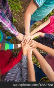 Close-up of many children's hands holding together as a team on a nature background