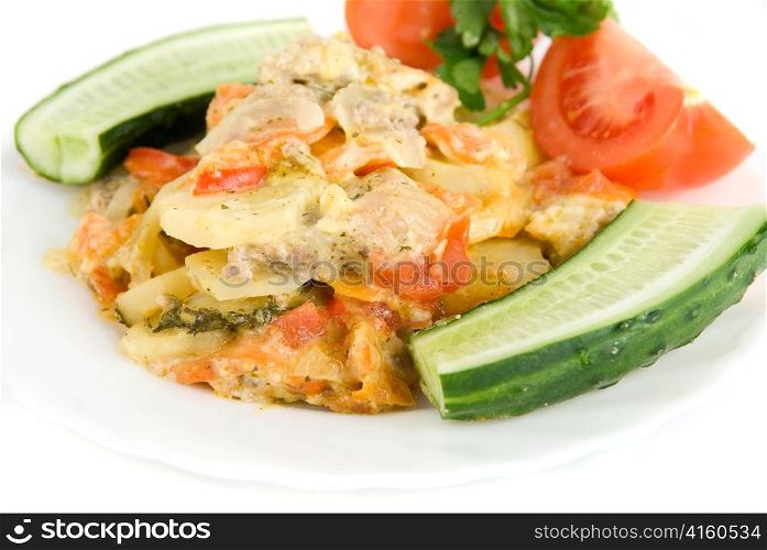Close up of meat, potatoes, tomatoes and cucumbers dish on white