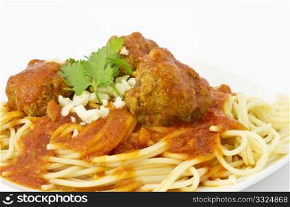 Close up of meatballs in red marinara sauce over spaghetti and garnished with cilantro sprigs and bits of romano cheese.
