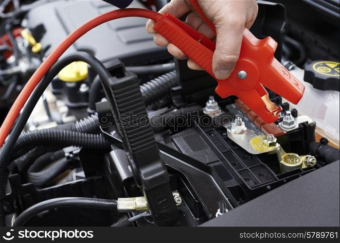 Close-Up Of Mechanic Attaching Jumper Cables To Car Battery