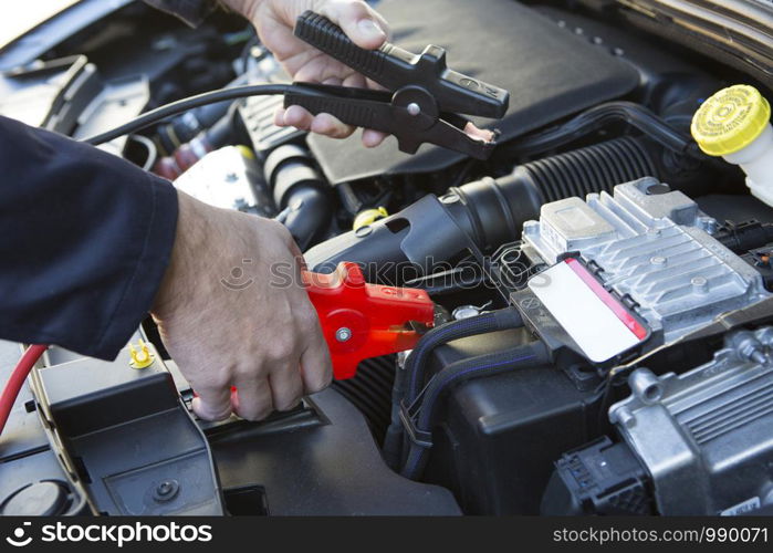 Close-Up Of Mechanic Attaching Jumper Cables To Car Battery