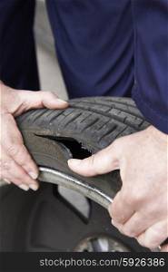 Close Up Of Mechanic Examining Damaged Car Tyre
