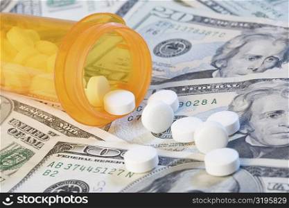 Close-up of medicines and a pill bottle on US paper currency