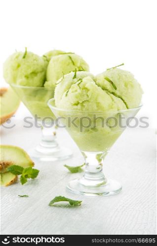 Close up of melon flavored ice-cream with mint and melon on a white table.