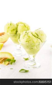 Close up of melon flavored ice-cream with mint and melon on a white table.