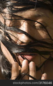 Close-up of mid-adult Asian female&acute;s face with wet hair.