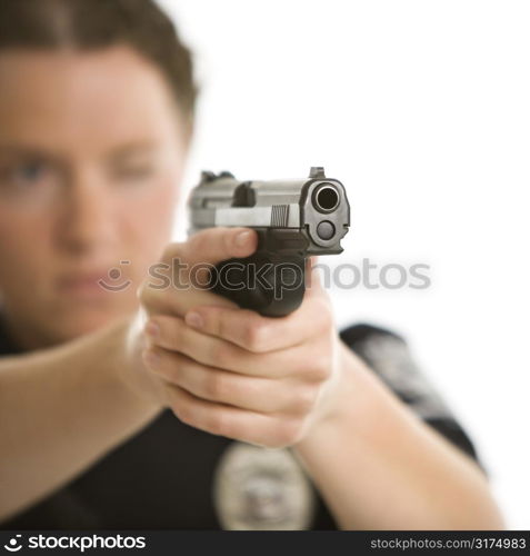 Close up of mid adult female Caucasian law enforcement officer aiming gun at viewer with one eye closed.