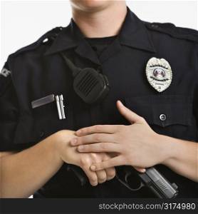 Close up of mid adult female Caucasian law enforcement officer with hands on gun.