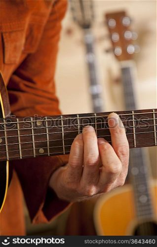 Close-up of mid adult man&acute;s fingers while playing guitar