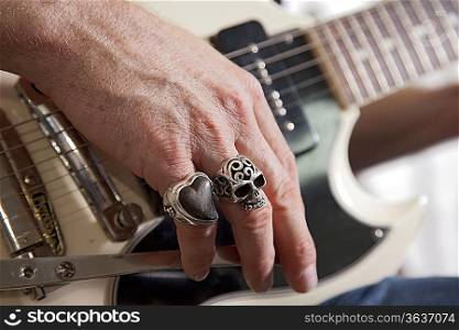 Close-up of mid adult man&acute;s fingers with rings playing guitar