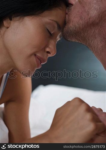 Close-up of mid-adult man kissing his girlfriend&acute;s forehead