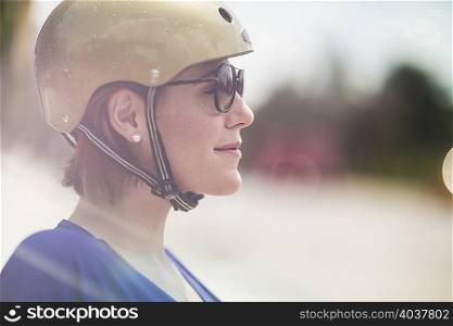 Close up of mid adult woman cyclist wearing cycle helmet and sunglasses