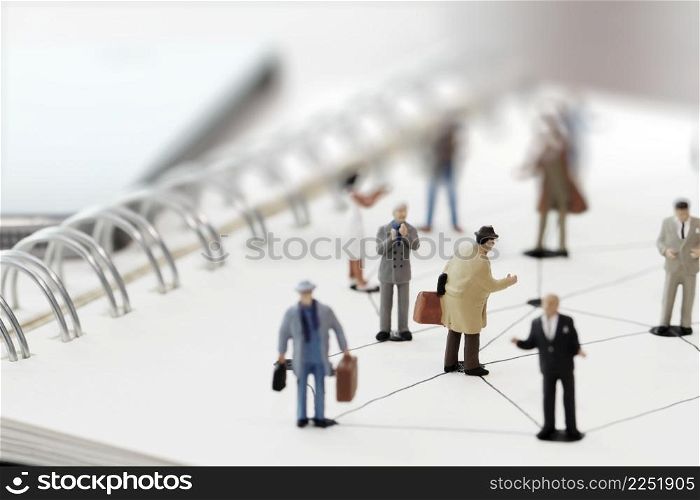 close up of miniature people with social network diagram on open notebook on wooden desk as social media conept