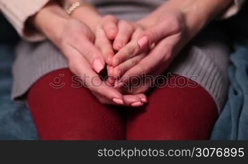 Close up of mother&acute;s hands holding and caressing her daughter&acute;s hands. Mom touching her kid with tenderness, expressing love, understanding and care. Focus on hands, front view.