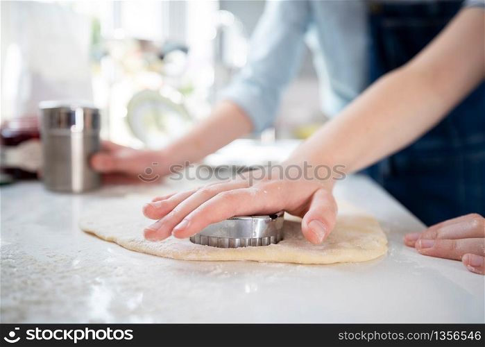 Close Up Of Mother And Daughter Using Pastry Cutter Baking In Kitchen At Home Together
