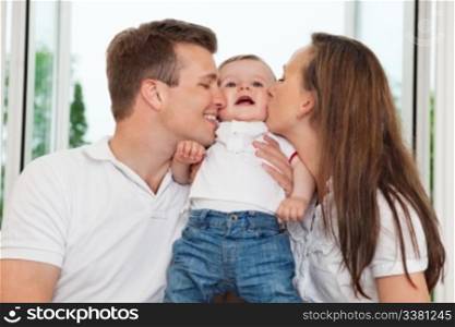 Close-up of mother and father kissing their child