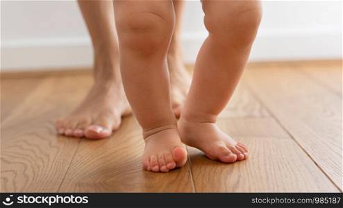 Close Up Of Mother Helping Baby Son To Take First Steps At Home