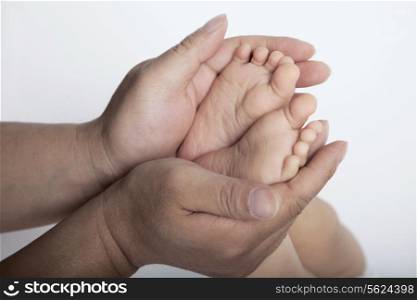 Close up of mothers hands holding the feet of her son, studio shot